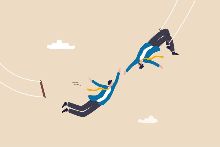 businessman trapeze perform jumping and catch by partner